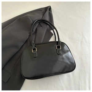 Detail of classic black leather shoulder bag with fine grain and golden hardware