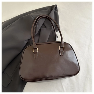 Macro detail of glossy dark brown leather shoulder bag with golden metal hardware