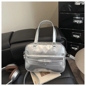 Detail of silver metallic handbag with bow accent and pleated texture on black sofa