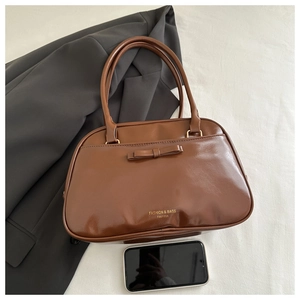 Top-down view of a brown vintage leather handbag with bow detail and zipper closure