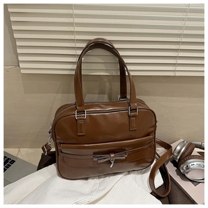 Brown vintage faux leather tote bag with bow detail and silver charm on office desk