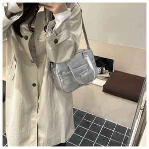 Detail view of silver metallic bow bag with star pendant on a model in urban setting
