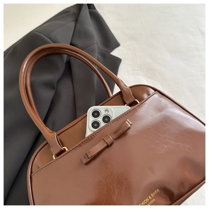 Detail of dark brown PU leather bag showing bow decor and interior phone storage capacity