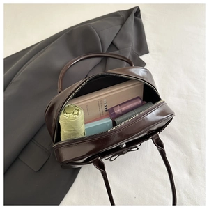 Detail view of large capacity brown glossy handbag showing interior storage for umbrella and books