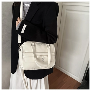 Detail of cream white JK style square bag with leather bow and silver heart charm