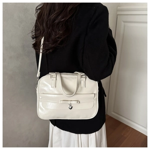 Detailed view of cream PU leather shoulder bag featuring bow decor and heart pendant