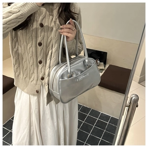 Chic silver crossbody bag with bow detail shown on a model in a mirrored reflection