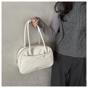 Detail of cream glossy leather pillow bag with bow and dual shoulder straps