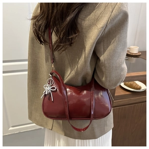 Elegant deep red underarm bag with rhinestone bow detail shown on a female model