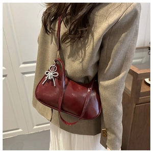 Vue détaillée du sac croissant en cuir ciré rouge foncé avec breloque nœud argenté