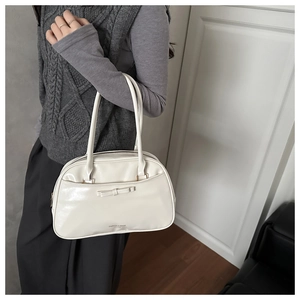 Detail view of cream vintage pillow bag featuring decorative bow and long handles