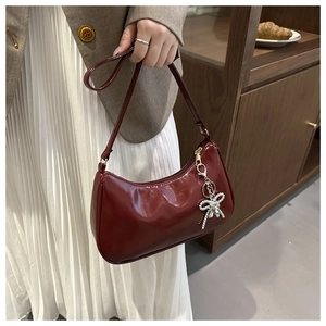 Detail van bordeauxrode laklederen hobo tas met een zilverkleurige kralen strik hanger