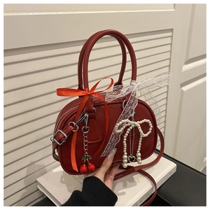 Detail of red leather bowling bag featuring cherry charms and lace ribbon bows