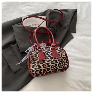 Close-up of leopard print handbag with red leather handles and white lace bow detail