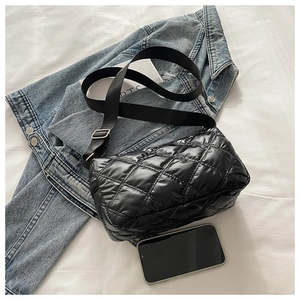 Detail of black quilted shoulder bag with soft nylon texture and wide adjustable strap