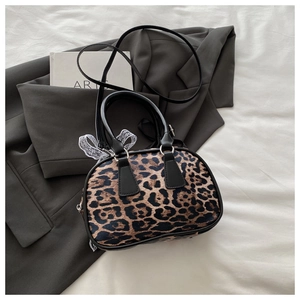 Detail view of leopard print handbag with leather strap on stylish blazer and book