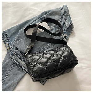 Macro detail of black quilted puffy crossbody bag showing diamond stitching texture