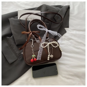 Detail of dark coffee vintage handbag with lace ribbons and cherry pendant charms