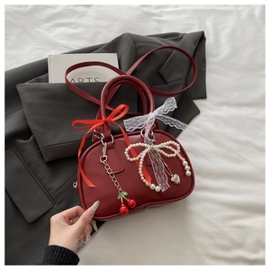 Detail of red matte Boston bag featuring cherry charms, pearl bows, and lace ribbons