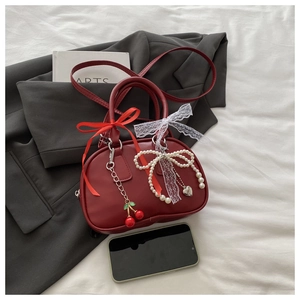 Macro shot of red faux leather handbag with pearl bows, cherries and lace charms