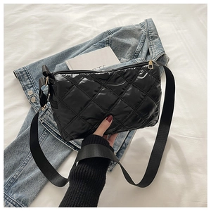 Detail of black quilted puffer crossbody bag with shiny nylon and wide woven strap