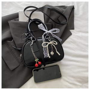 Detail of black mini handbag with lace bow and cherry pearl charm accessories