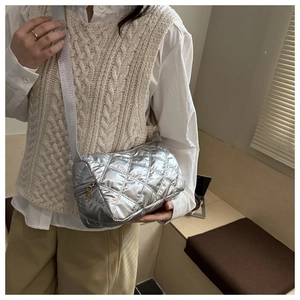 Detail of silver quilted puffer crossbody bag with adjustable strap and metal zipper