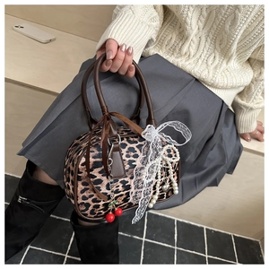 Detailed close-up of leopard print Boston bag with lace bow and cherry charms