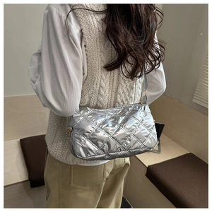 Silver quilted crossbody bag with diamond stitch and gold zipper shown on a model