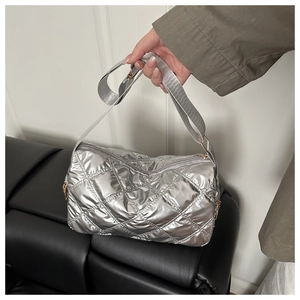 Detail of silver quilted puffer crossbody bag featuring large rhombic stitching and golden zipper