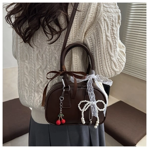 Detail of vintage leopard print handbag featuring lace ribbons and pearl cherry charm