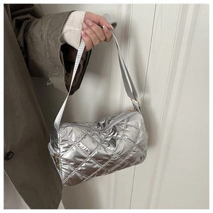 Detail of silver quilted puffer bag showing textured cross-stitch and adjustable strap