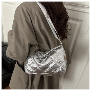 Detail of silver quilted shoulder bag with white wide strap shown on model's shoulder