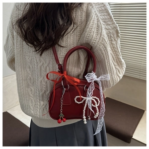 Detail of red vintage crossbody bag with cherry charms and silk lace bows decoration