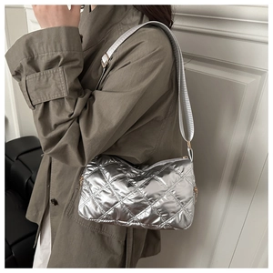 Detail of silver quilted crossbody pillow bag with metallic finish and wide strap
