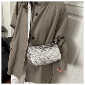 Detail of silver quilted pillow bag with metallic finish and wide white strap