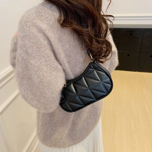 Minimalist black crescent shoulder bag with quilted diamond pattern on casual model outfit