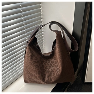 Close-up of leopard print suede hobo bag with wide shoulder strap and silver buckle