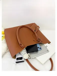 Detail showing the large interior capacity of this brown tote bag with various daily essentials