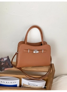 Close-up of brown pebbled leather texture and silver clasp on retro square handbag