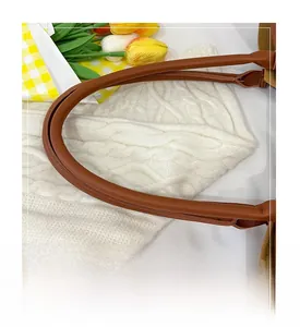 Detail of soft brown leather tote bag handle with uniform stitching on knit fabric