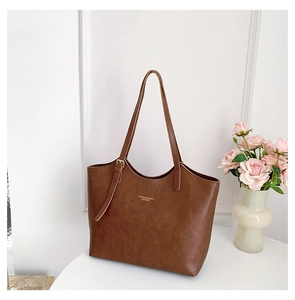 Detail of vintage brown tote bag with gold lettering and adjustable strap on white table