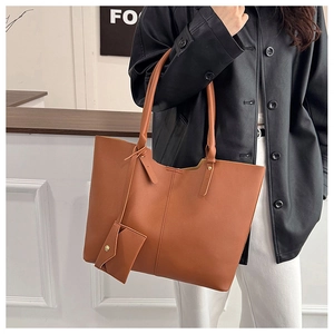 Brown faux leather tote bag with mini zipper pouch worn by model in city style