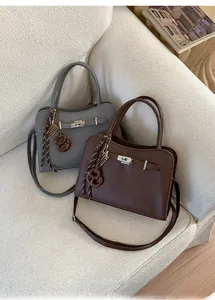 Detail of lychee pattern leather handbag with silver twist lock and woven charm
