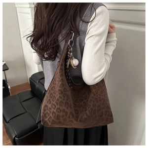 Detail of leopard print suede hobo bag featuring wide strap and baseball charm