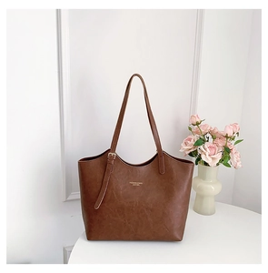Detailed texture of dark brown leather tote with golden lettering on a white table