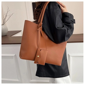Close-up of caramel brown leather tote bag with matching envelope pouch and gold metal hardware