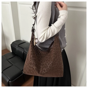 Detail of leopard print crossbody bag with baseball charm on a fashion model