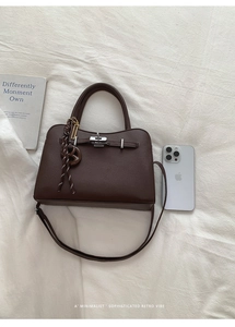 Close-up of brown litchi pattern leather Kelly bag with silver hardware and pretzel charm