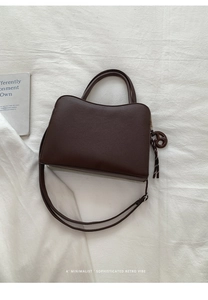 Detail of dark brown pebbled leather texture on minimalist retro handbag with dual handles